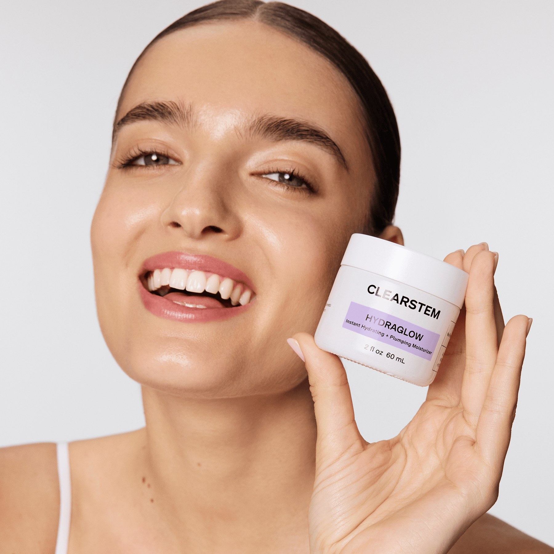 A model cradles the HYDRAGLOW Plant Stem Cell Moisturizer jar, the top selling topical in the range.
