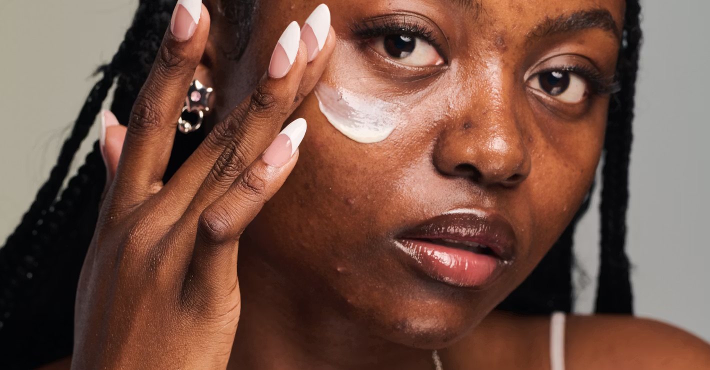 Close portrait of a model smoothing skincare cream on skin.