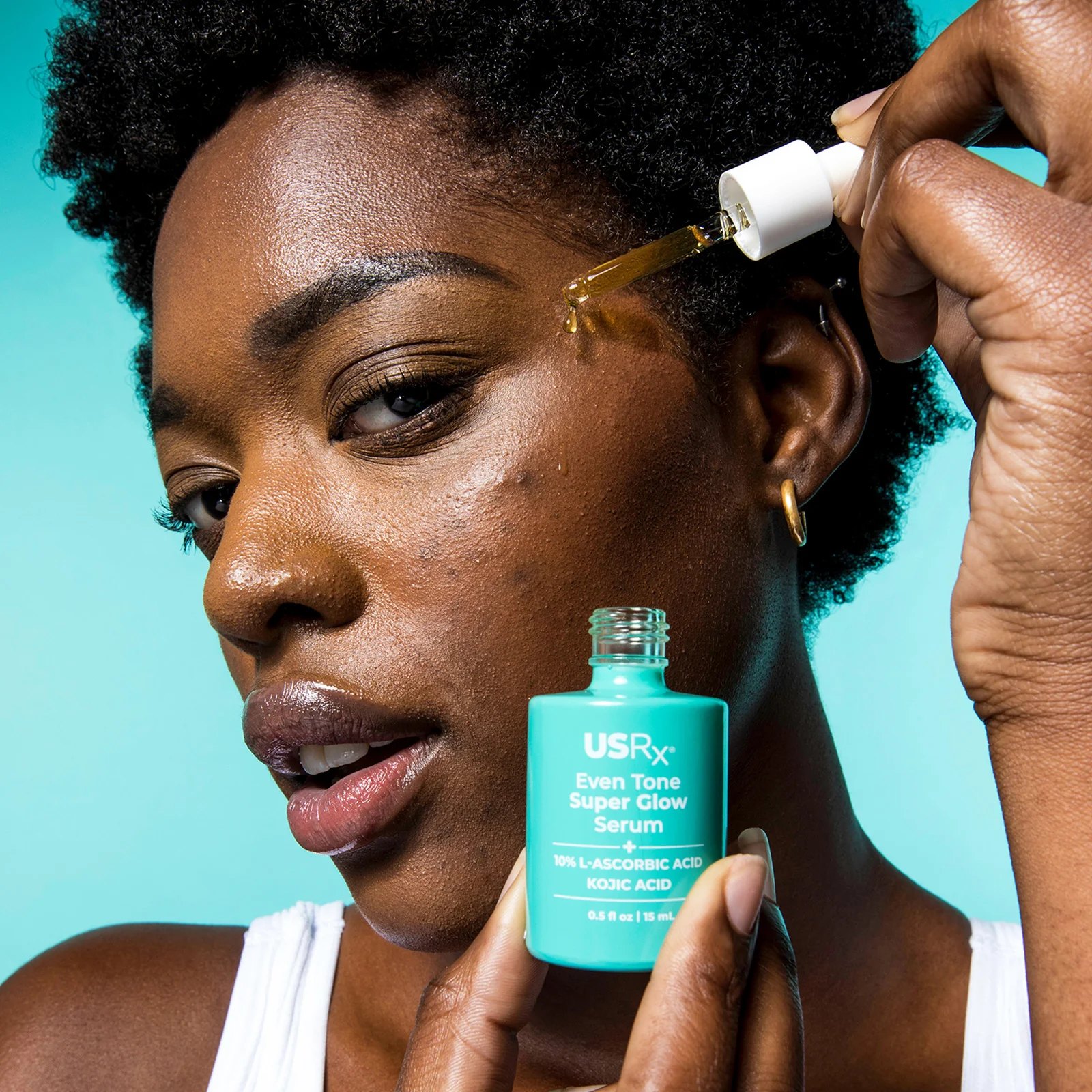 Close view of model using the serum dropper on her face.